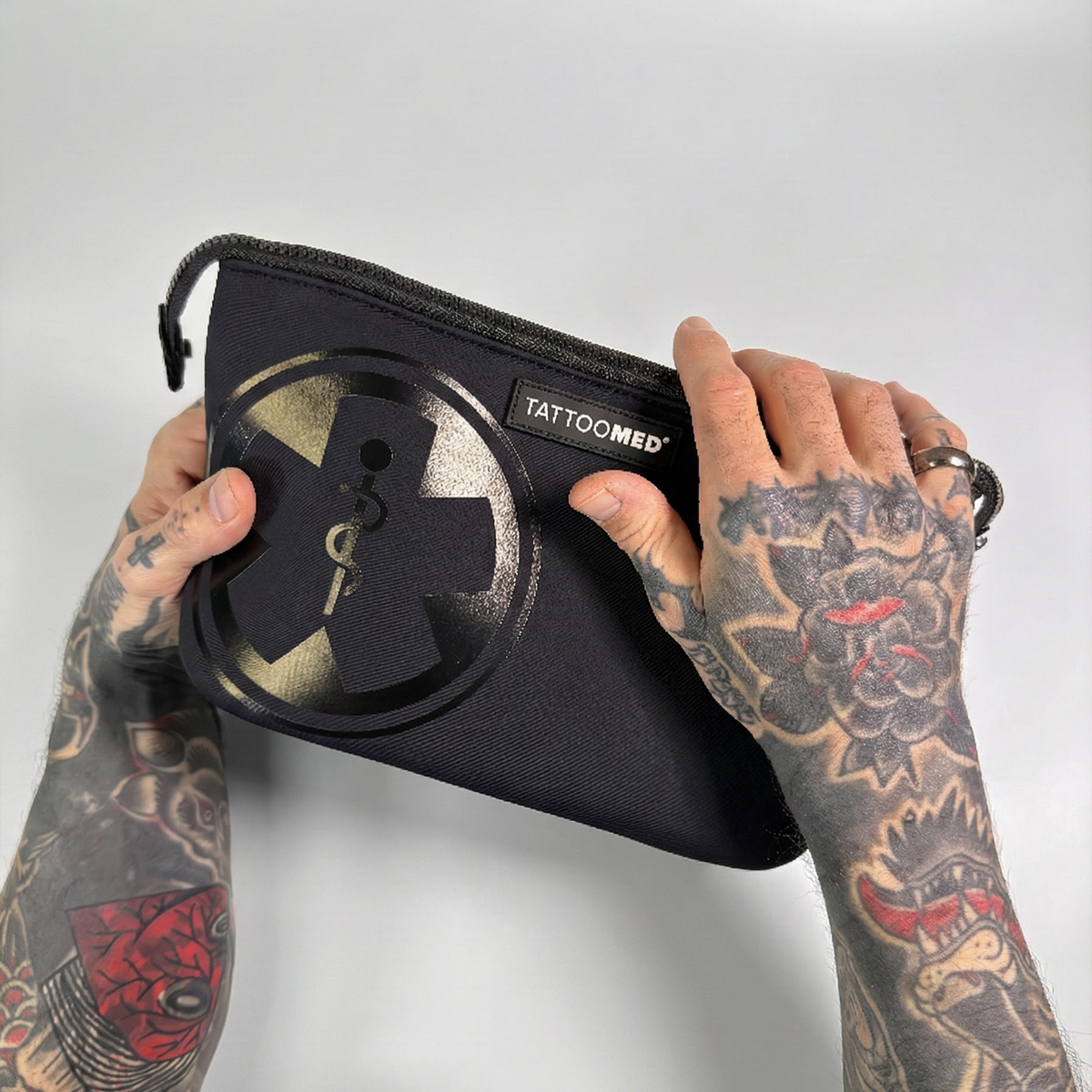 TattooMed Care Bag. Kosmetiktasche wird von tätowierten Händen gehalten