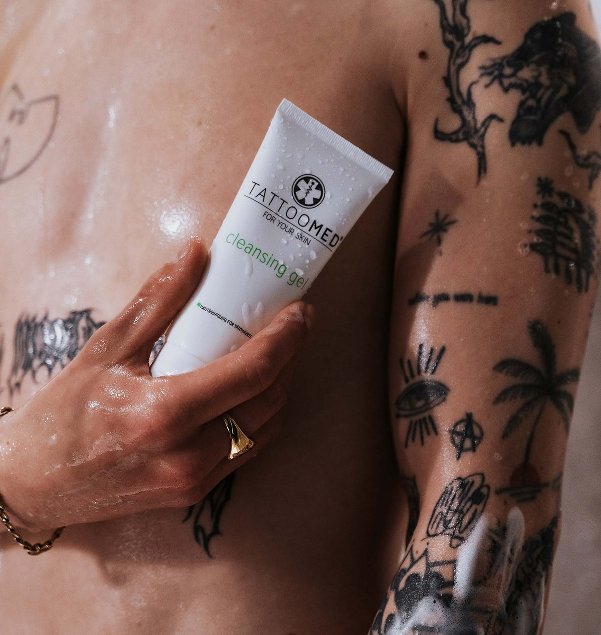 TattooMed Cleansing Gel in tätowierter Hand unter der Dusche.