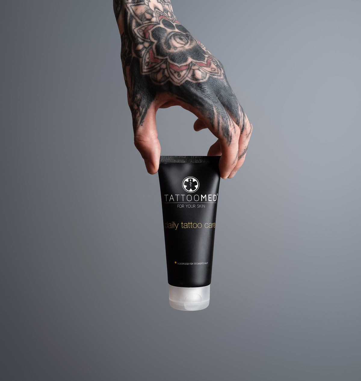 Tätowierte Hand hält TattooMed Daily Tattoo Care