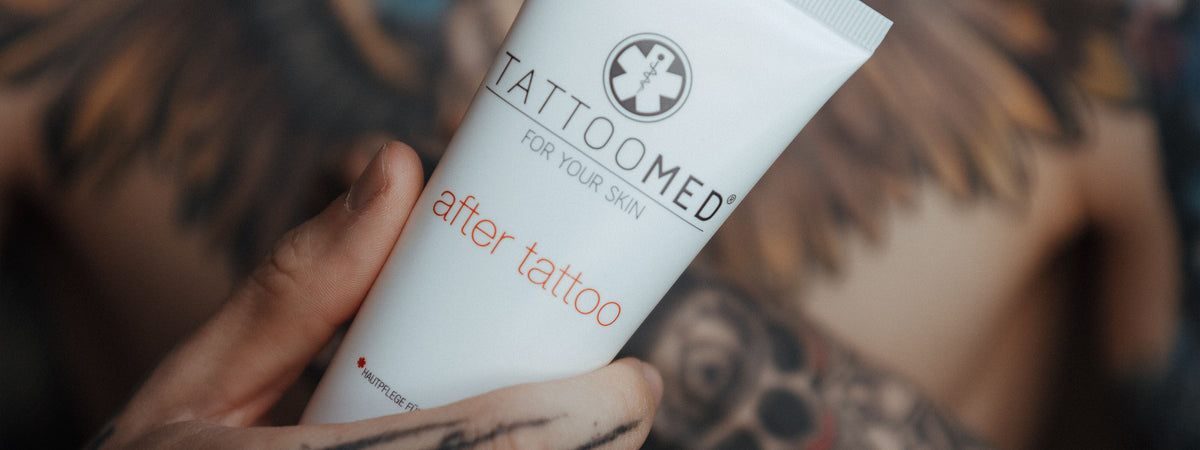 Tätowierter Mann hält TattooMed Tube in die Kamera