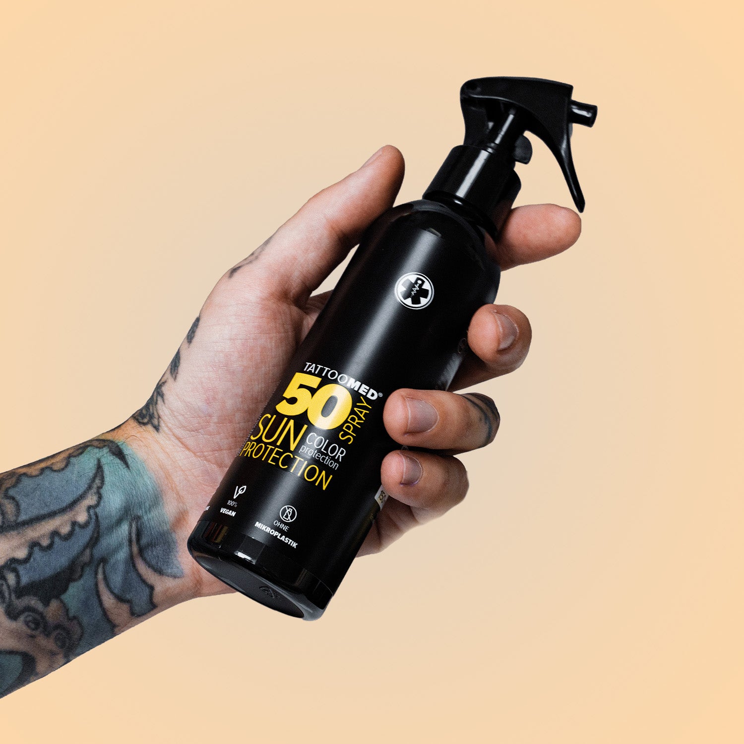 Tätowierte Hand hält TattooMed Sun Protection Spray LSF50