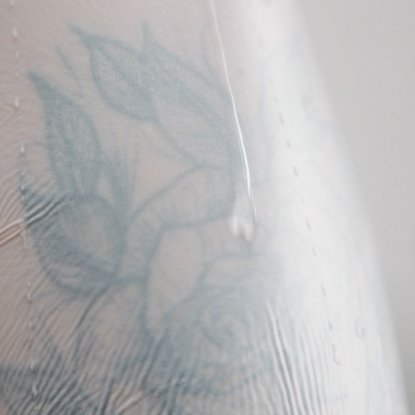 TattooMed UV Patch Milky auf tätowierter Haut - Nahaufnahme mit Wassertropfen