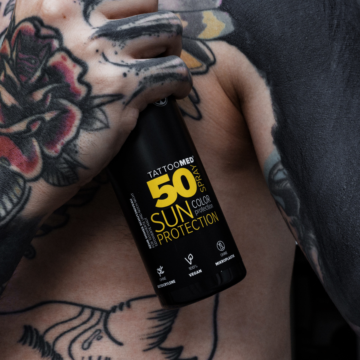 TattooMed® sun protection LSF50 spray 150ml vor einer tätowierten Person