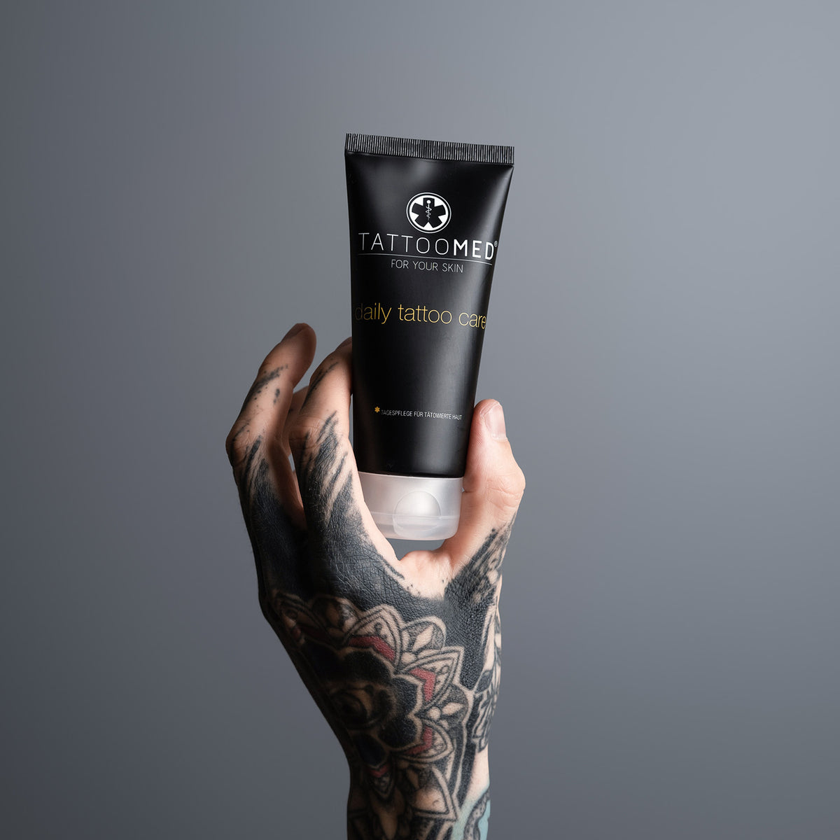 Tätowierte Hand hält TattooMed Tube