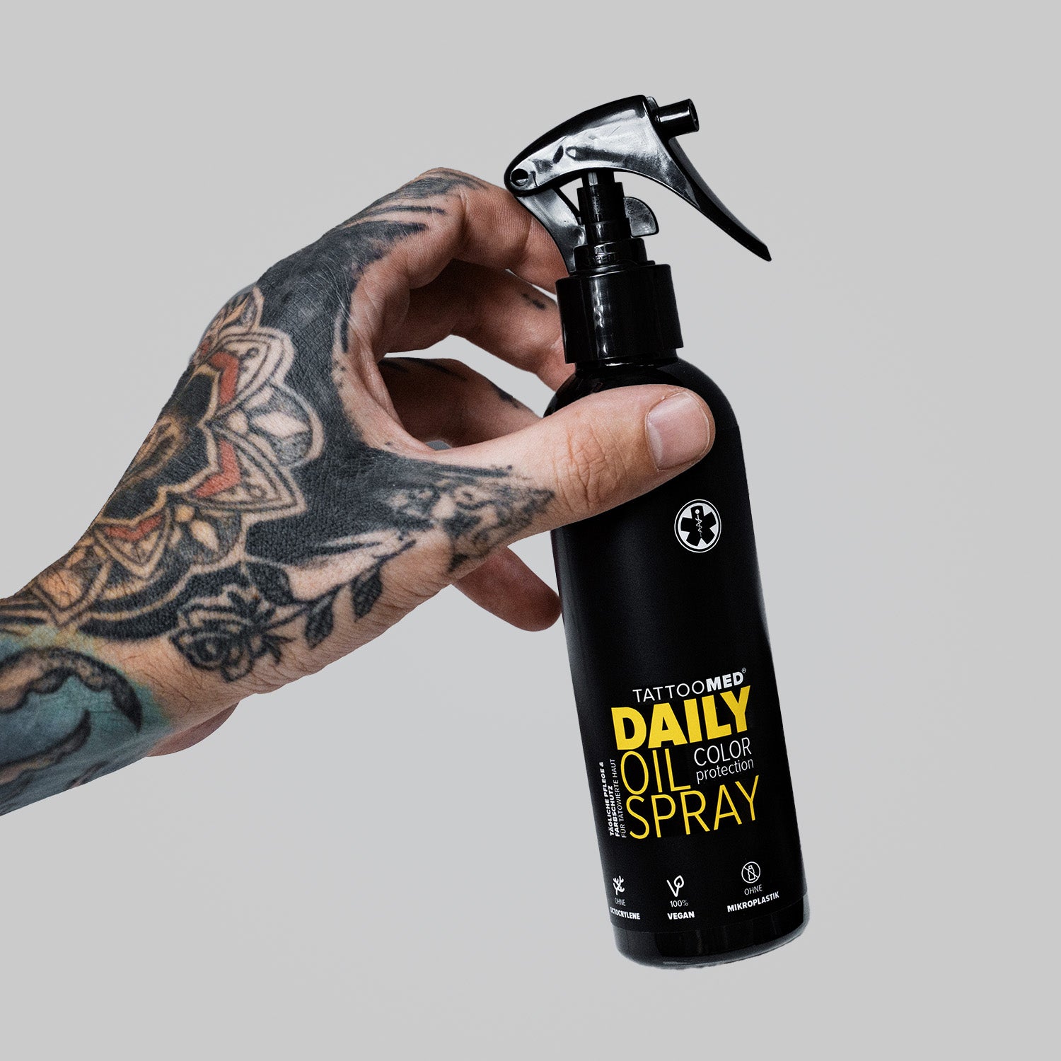 TattooMed Daily Oil Spray gehalten von einer tätowierten Hand