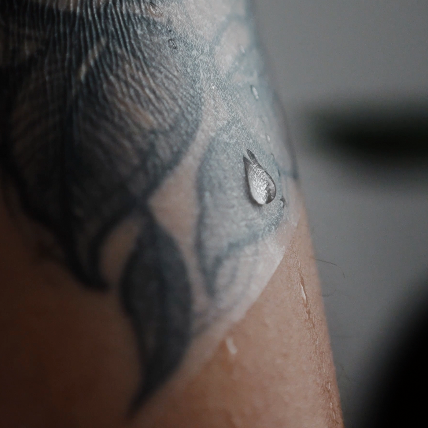 Wassertropfen auf TattooMed Protection Film, der auf tätowierter Haut klebt