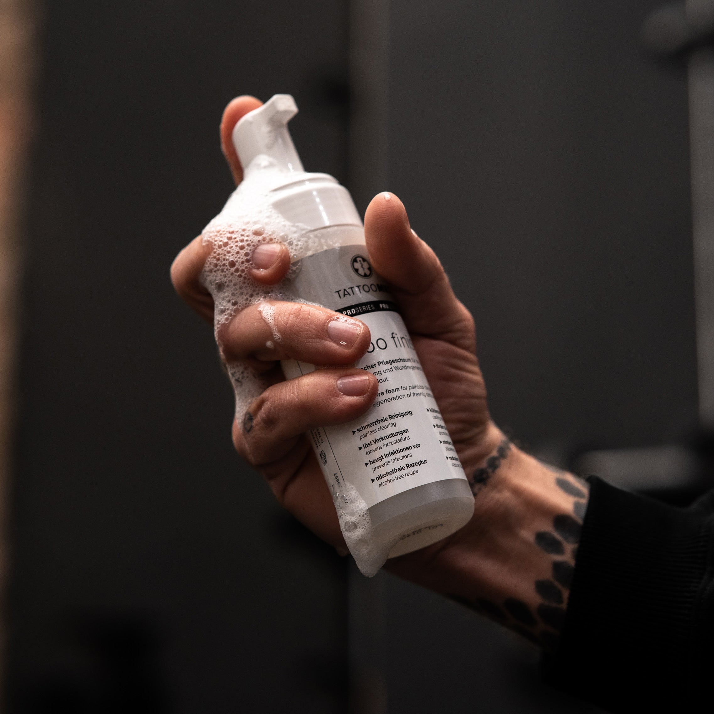 TattooMed Tattoo Finish in tätowierter Hand. Schaum läuft an der Hand herunter