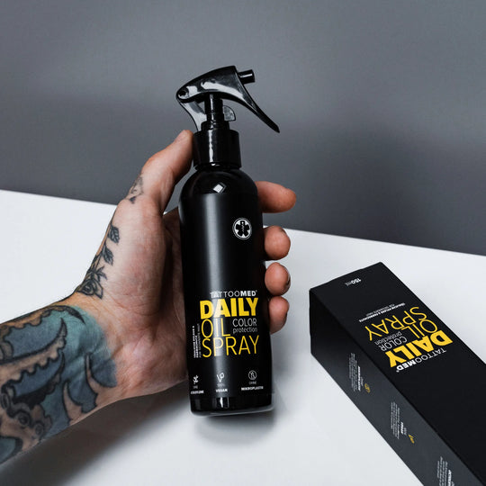 TattooMed® daily oil spray 150ml in einer tätowierten Hand